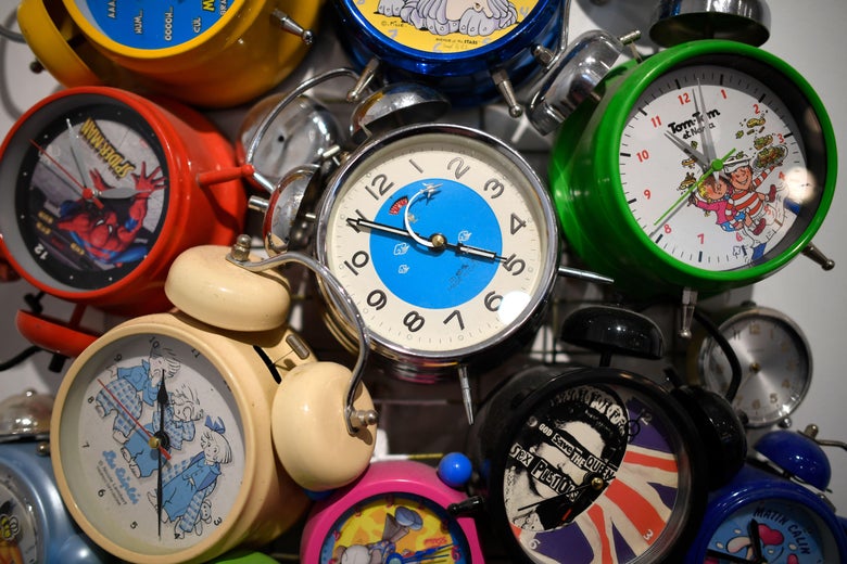 Several analog alarm clocks with different decorations sit in frame.